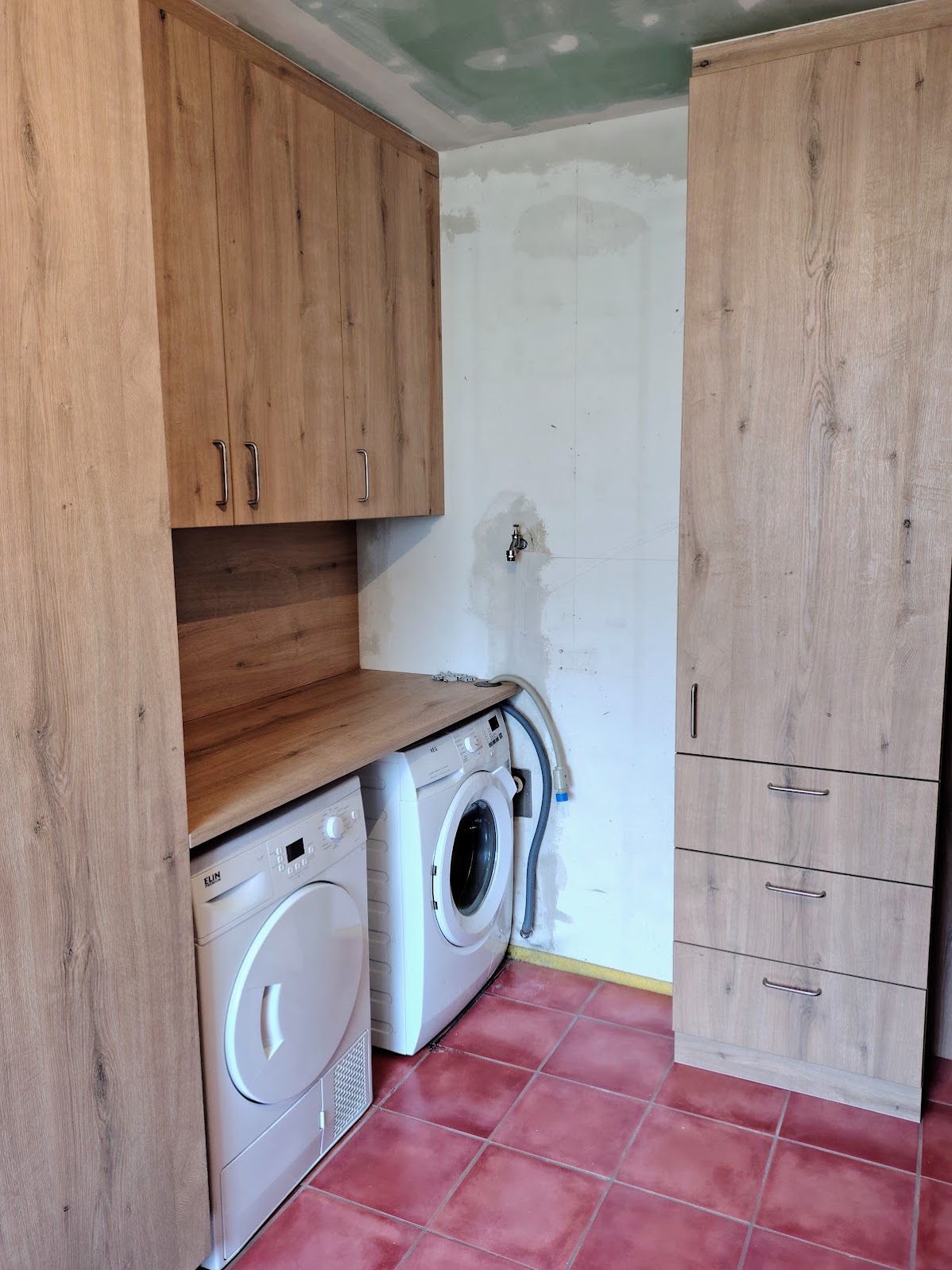 Projektfoto: Maßmöbel mit Waschmaschine, Trockner und Stauraum in einem schmalen Hauswirtschaftsraum