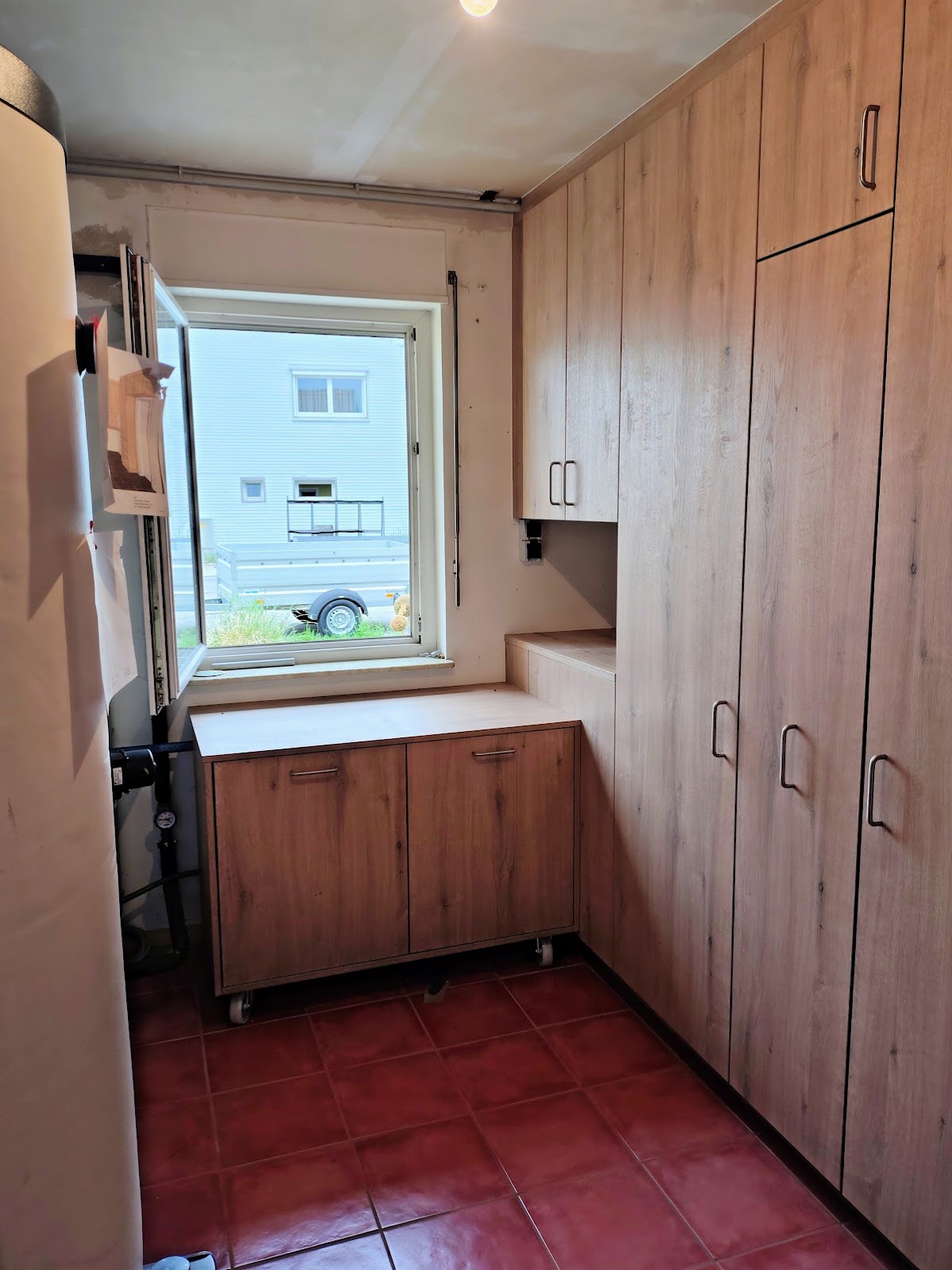 Projektfoto: Hochschränke und Stauraummöbel am Fenster eines schmalen Hauswirtschaftsraums